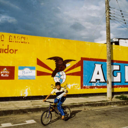 <p>A boy cycling through town.</p>