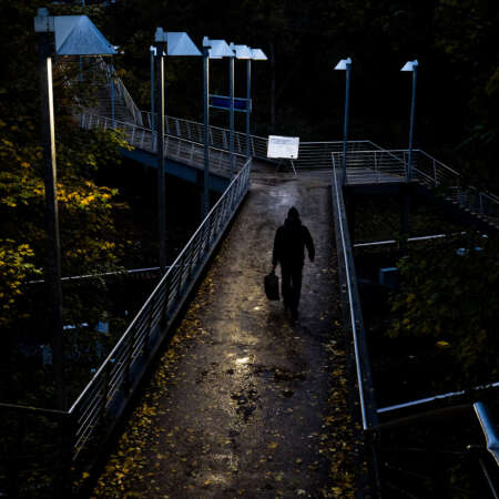 <p>A man crosses an elevated walkway where a notice awaits him.</p>