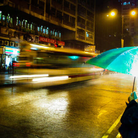 <p>A woman shields herself from one of Hong Kong's sudden, torrential rain storms.</p>