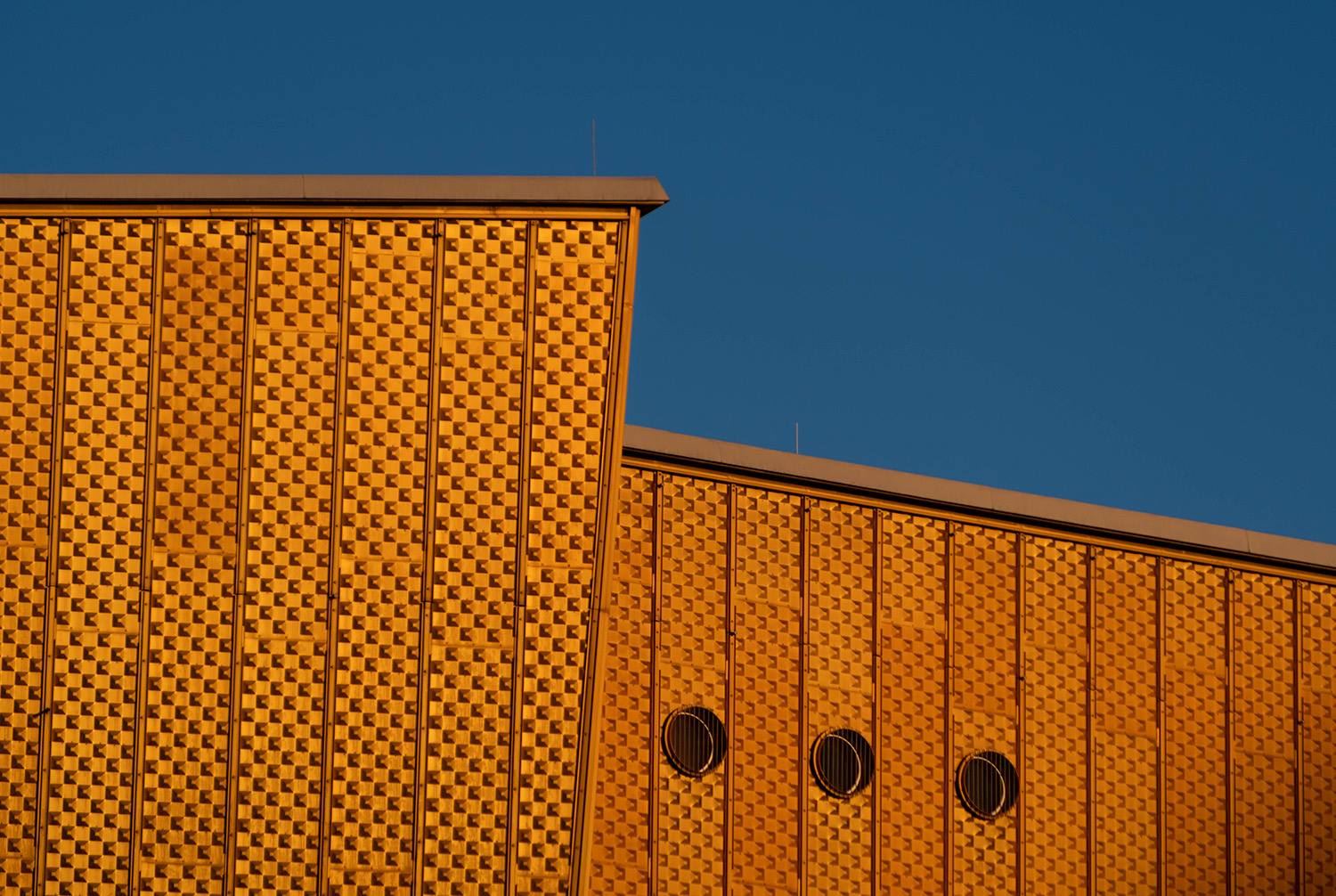 <p>A detail of the golden cladding and angular roofline of the Kammermusiksaal (chamber music hall) at the Philharmonie complex in Berlin.</p>