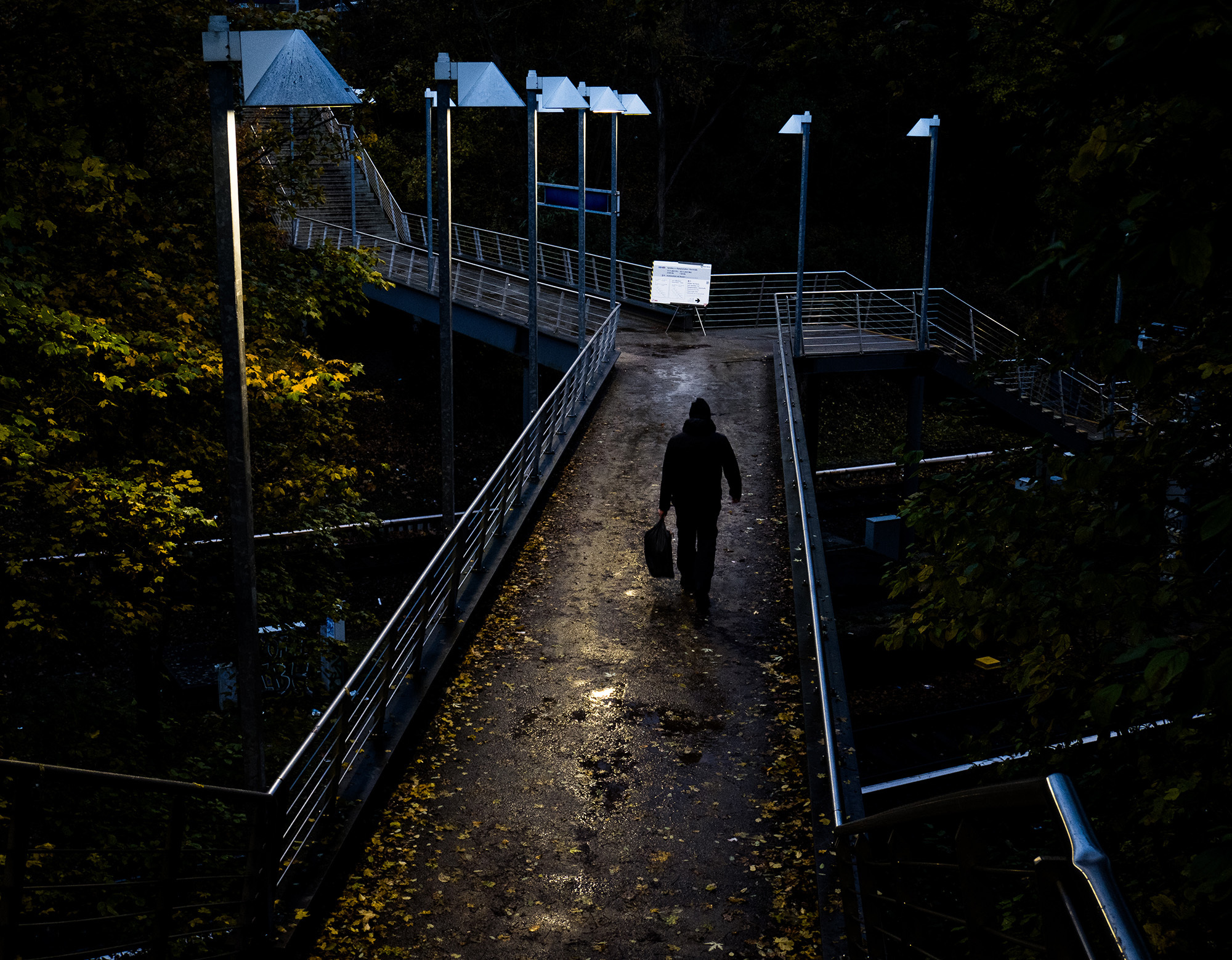 <p>A man crosses an elevated walkway where a notice awaits him.</p>