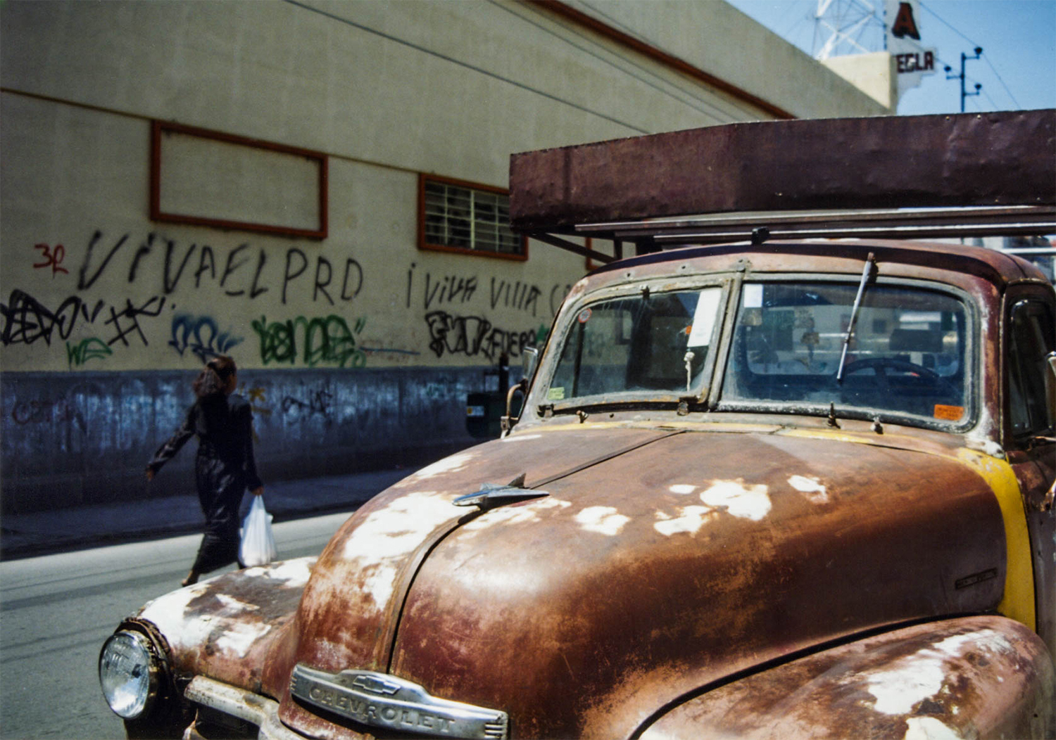 <p>A Poblana passes an old truck and graffiti promoting the centre-left PRD party.</p>