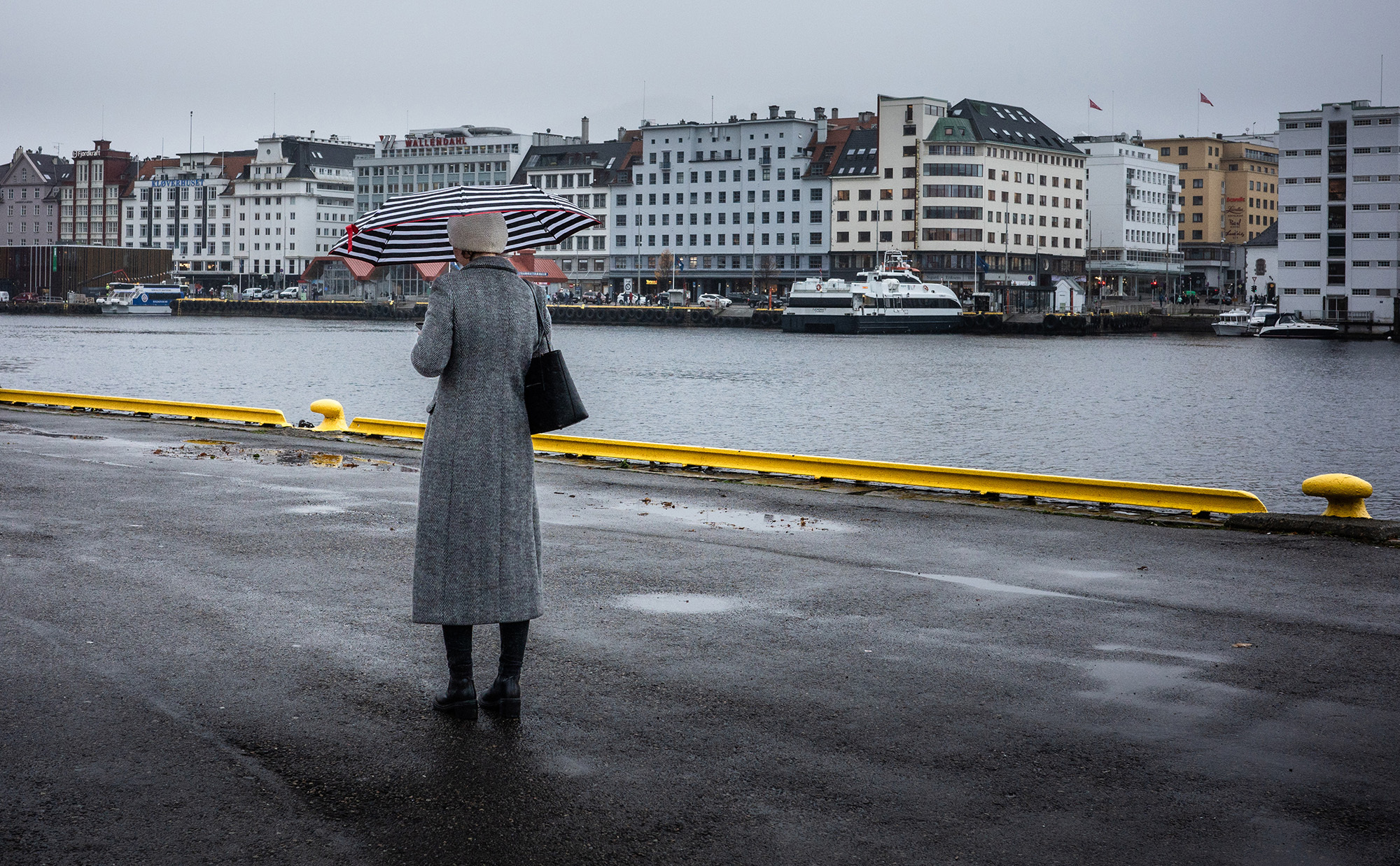 <p>A person stops momentarily on a rainy morning along Bergen's waterfront.</p>