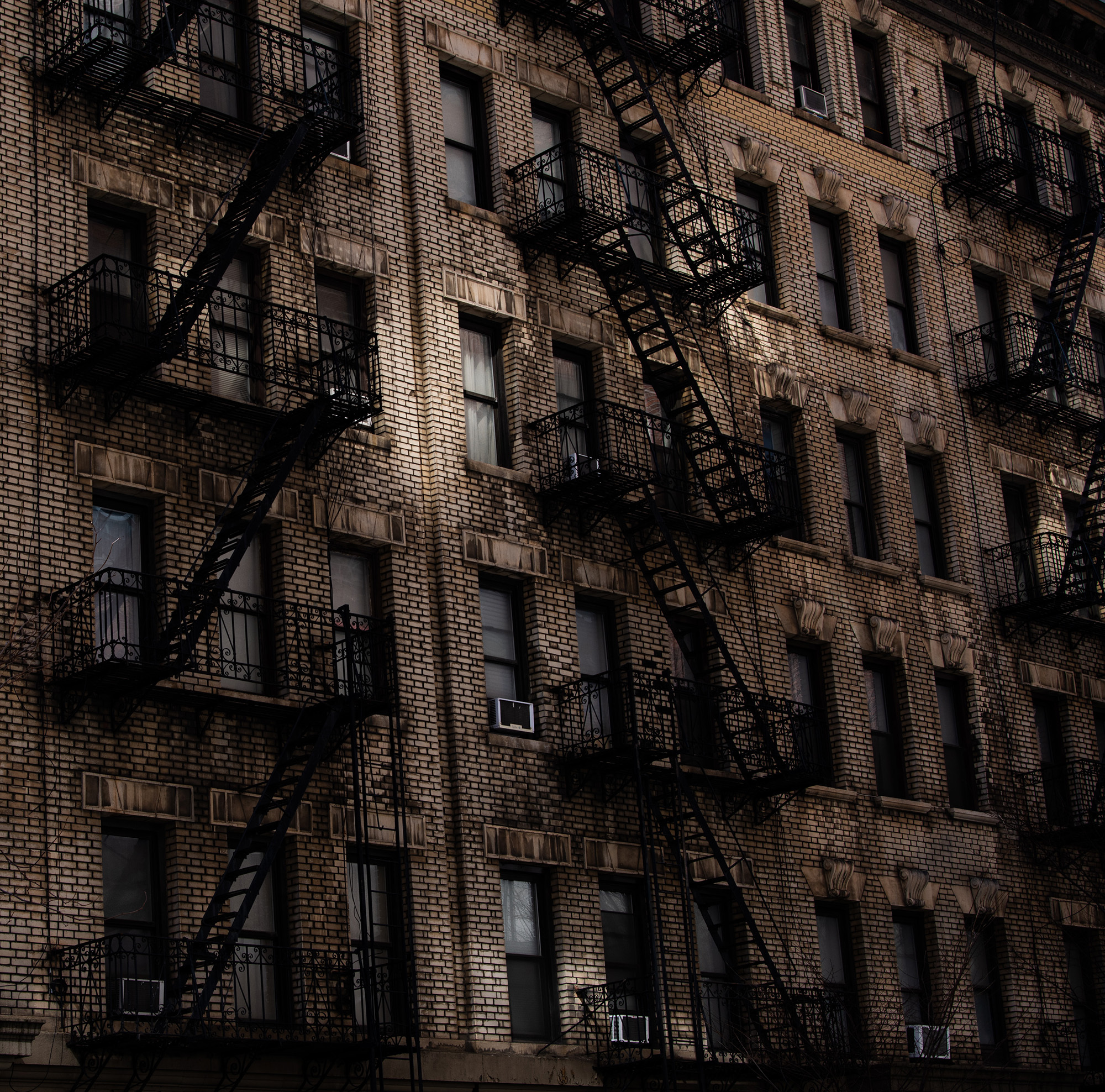 <p>Reflections bounce sunlight onto the bricks and characteristic fire escapes of some New York apartments.</p>